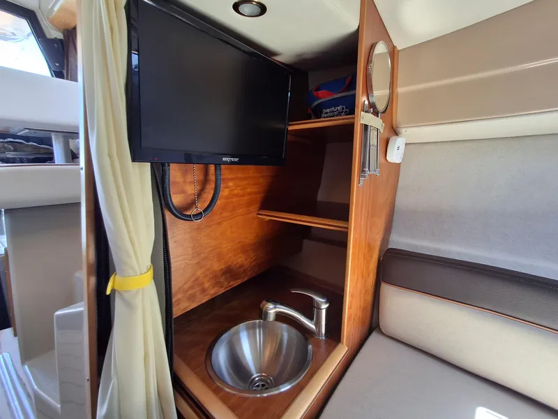 Slide: The Image of 2017 Cutwater C24 interior with TV, sink, and wooden cabinetry. - 18