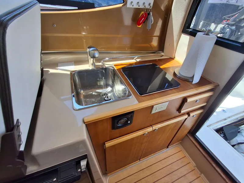 Slide: The Image of 2017 Cutwater C24 boat interior kitchen with sink, stove, and wooden cabinetry. - 24