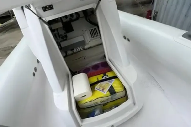 Slide: The Image of 2023 Airship 310-Rib boat interior with white seating and audio system, docked near a warehouse. - 24