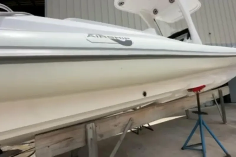 Slide: The Image of 2023 Airship 310-Rib boat on stands, dockside with tropical surroundings. - 3