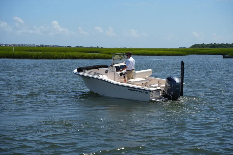 Slide: The Image of 2024 Grady-White Fisherman 180 boat cruising on a calm river under a clear sky. - 11