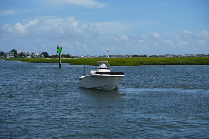 Slide: The Image of 2024 Grady-White Fisherman 180 boat cruising on a calm waterway under a clear blue sky. - 6