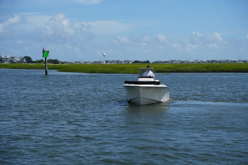 Slide: The Image of 2024 Grady-White Fisherman 180 boat cruising on a calm waterway under a clear blue sky. - 7