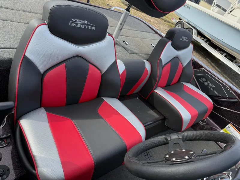 Slide: The Image of 2021 Skeeter ZX 150 boat seats, red and gray design, with steering wheel visible. - 12