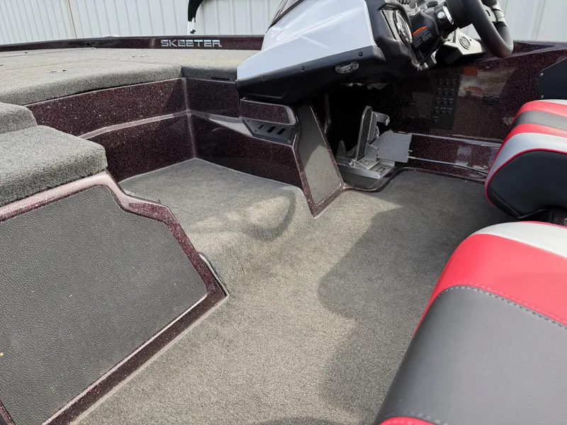 Slide: The Image of 2021 Skeeter ZX 150 boat interior with red and gray seating, steering console, and carpeted flooring. - 16