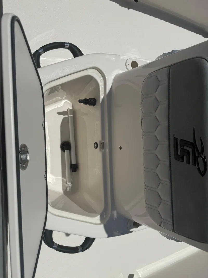 Slide: The Image of 2025 Carolina Skiff 19 LS boat storage compartment with cushioned seat and handle. - 11