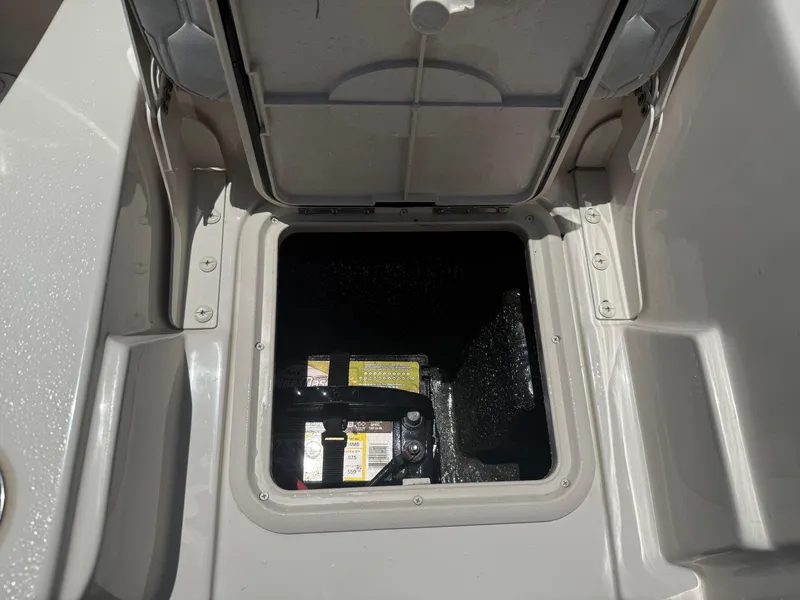 Slide: The Image of Open storage compartment on 2025 Carolina Skiff 19 LS boat, revealing battery inside. - 18