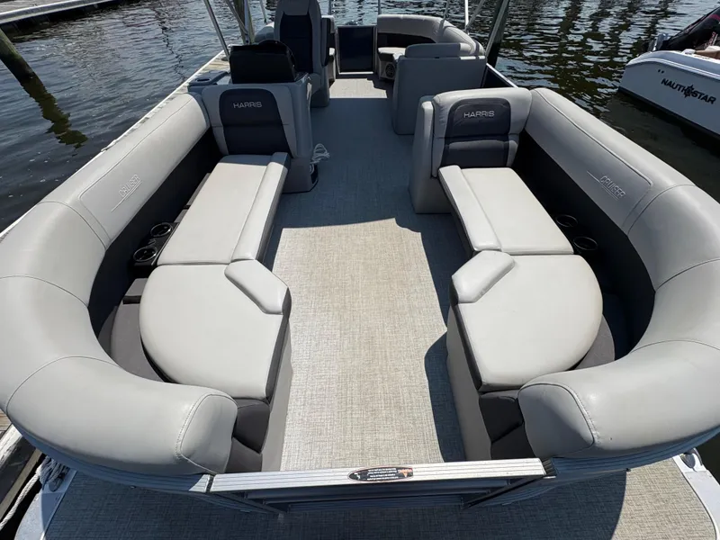 Slide: The Image of 2024 Harris Cruiser 230 pontoon boat with spacious seating, docked on calm water. - 3