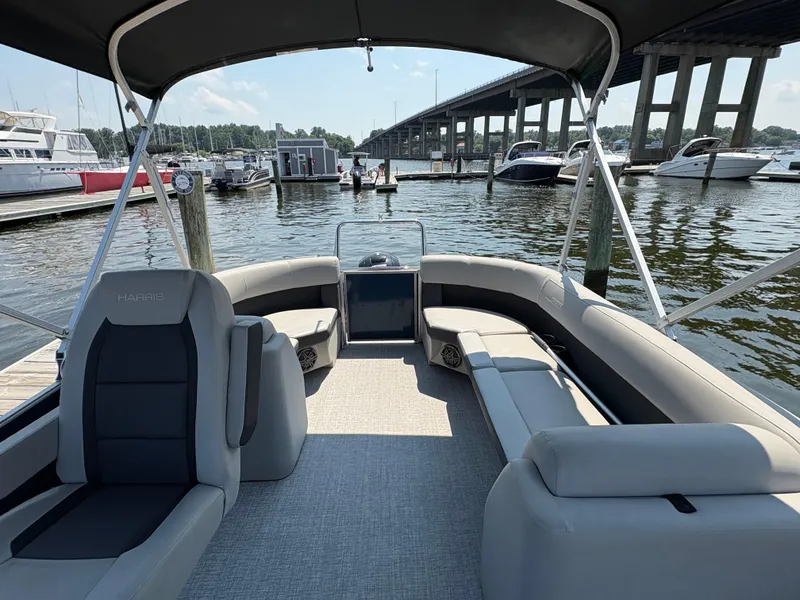 Slide: The Image of 2024 Harris Cruiser 230 pontoon boat interior at marina, featuring spacious seating and modern design. - 4