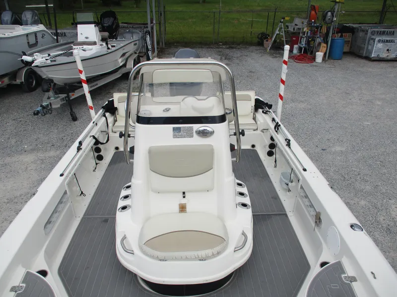 Slide: The Image of 2015 NauticStar 224 boat interior with seating and steering console, parked on gravel. - 3
