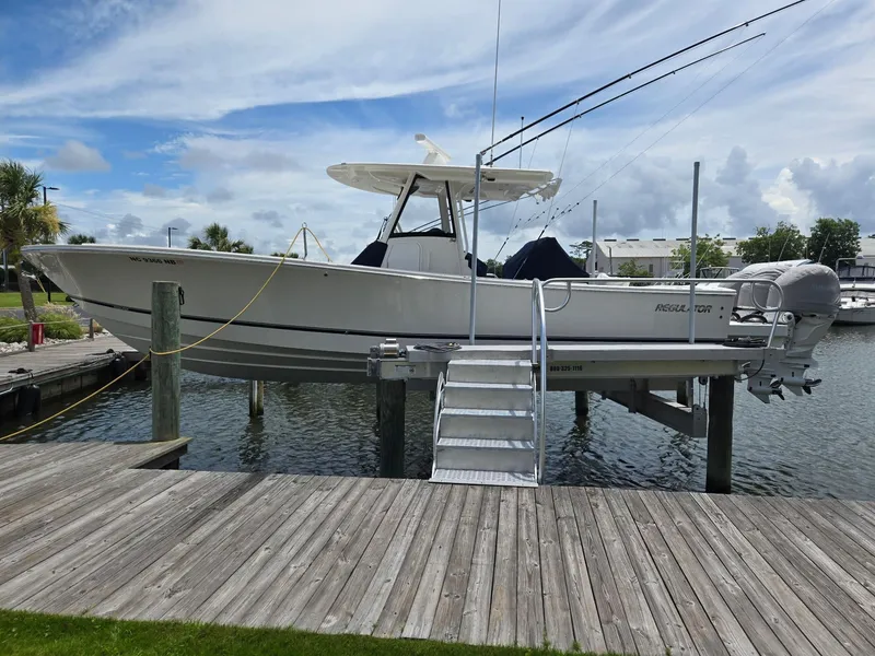 The Image of 2023 Regulator 34 boat docked on lift, with fishing rods and clear sky background. - 1