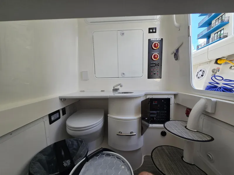 Slide: The Image of Interior of 2023 Regulator 34 boat featuring a compact bathroom with sink and toilet. - 12