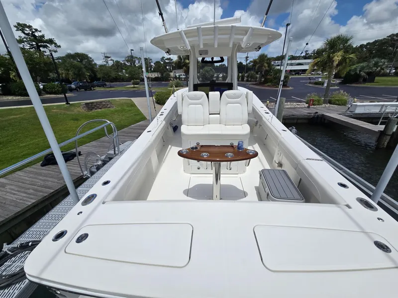 Slide: The Image of 2023 Regulator 34 boat with spacious deck, seating, and fishing rod holders, docked under cloudy skies. - 24