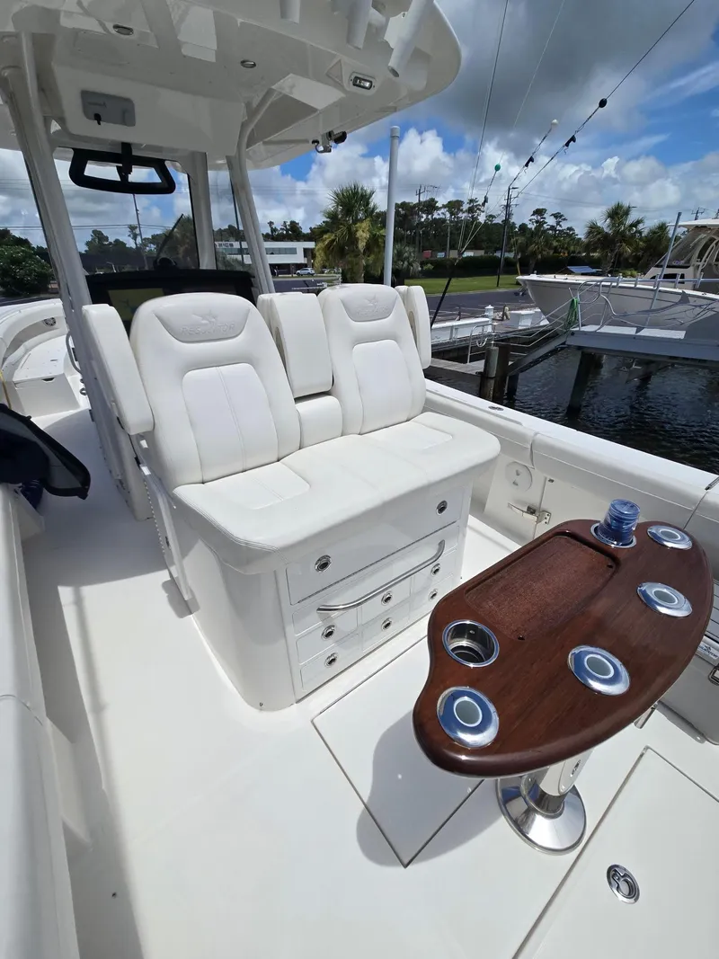 Slide: The Image of 2023 Regulator 34 boat interior with white seating and wooden table, docked at marina. - 25