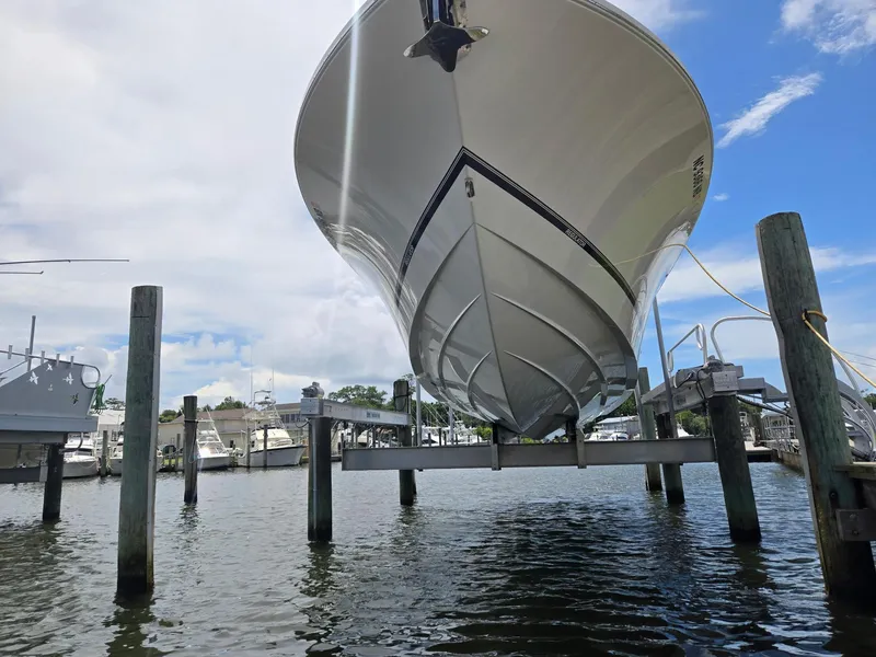 Slide: The Image of 2023 Regulator 34 boat on lift at marina, under a partly cloudy sky. - 5