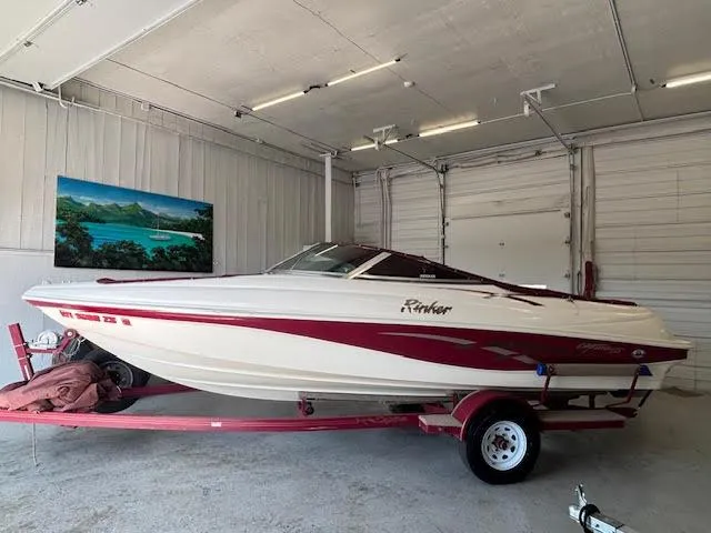 Slide: The Image of 2000 Rinker Captiva 212 boat in garage, white and red design, on trailer. - 2