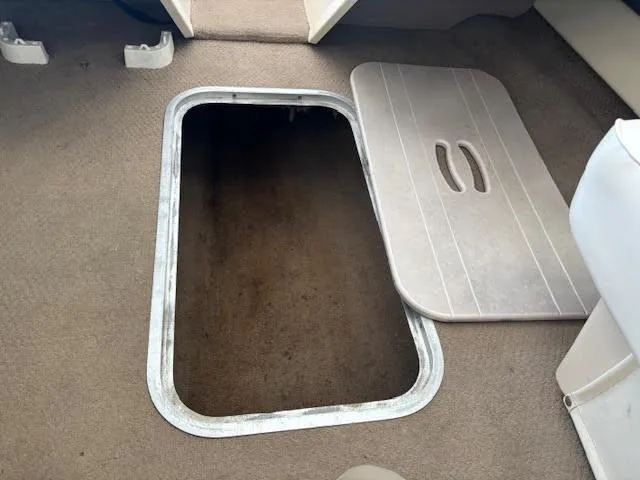 Slide: The Image of Open storage compartment on 2000 Rinker Captiva 212 boat with carpeted interior. - 24
