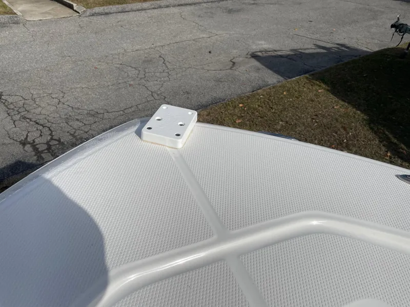 Slide: The Image of 2024 Robalo 226 Cayman boat deck with mounting bracket, textured surface, and outdoor setting. - 16