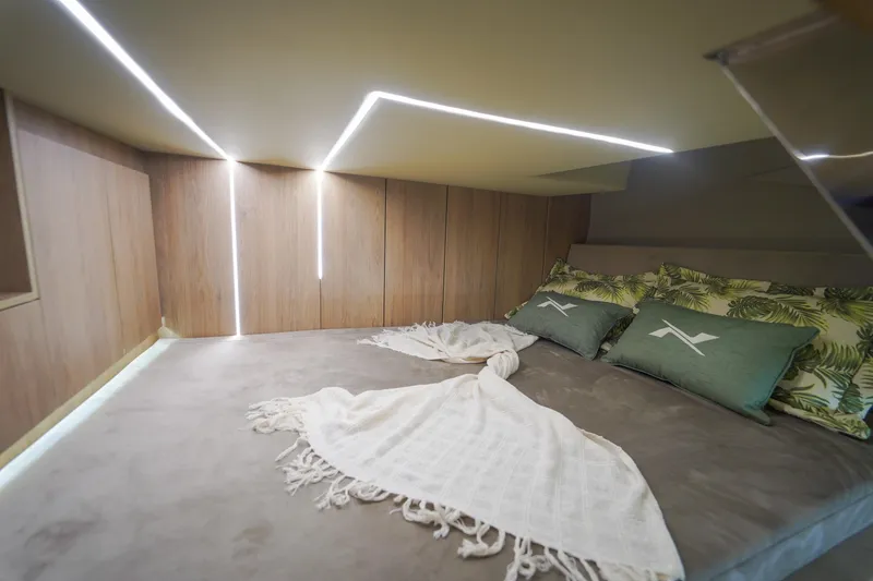 Slide: The Image of 2024 NX Boats NX360 Sports Coupe cabin with modern lighting and cozy bedding. - 12
