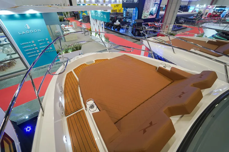 Slide: The Image of 2024 NX Boats NX360 Sports Coupe at a boat show, featuring a spacious deck with brown seating. - 9