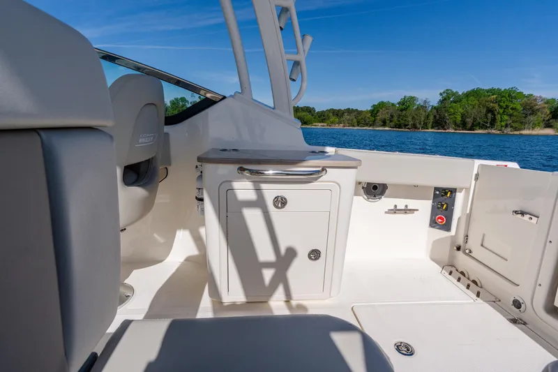 Slide: The Image of 2022 Boston Whaler 240 Vantage interior, featuring seating and storage, with scenic water view. - 23