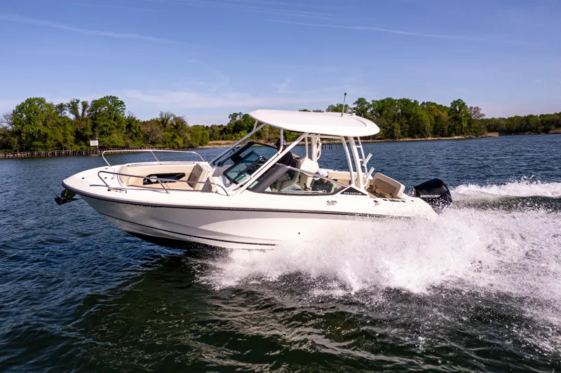 Slide: The Image of 2022 Boston Whaler 240 Vantage cruising on a scenic lake with lush green shoreline. - 9