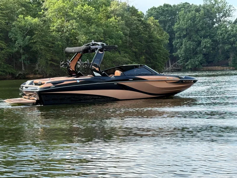 Slide: The Image of 2022 Centurion Fi23 boat on a calm lake with lush green trees in the background. - 11