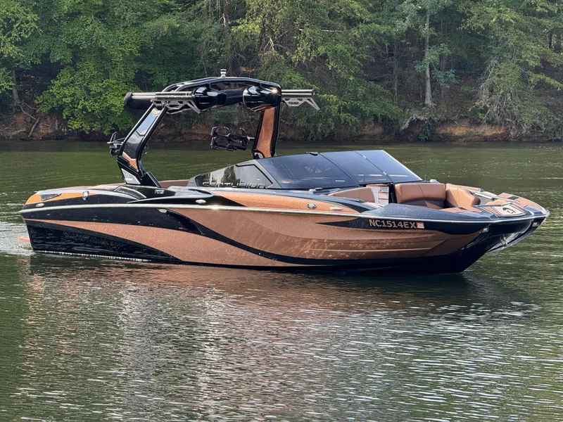 Slide: The Image of 2022 Centurion Fi23 boat on a calm lake with lush green forest background. - 12