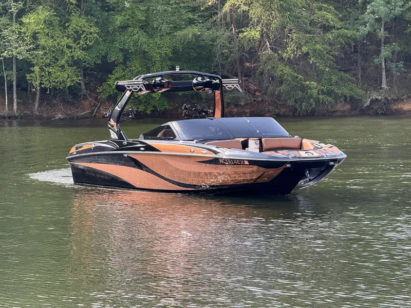 Slide: The Image of 2022 Centurion Fi23 boat on a calm lake with lush green forest backdrop. - 13