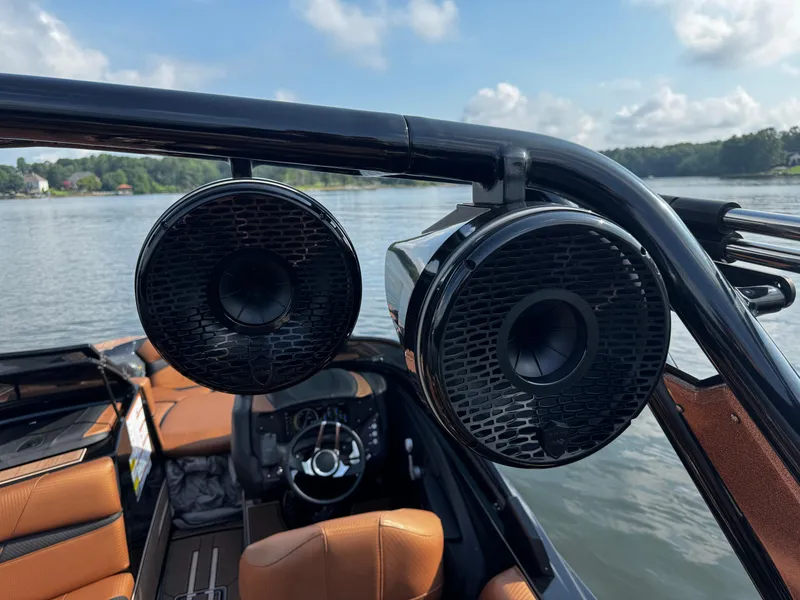 Slide: The Image of 2022 Centurion Fi23 boat with mounted speakers, brown interior, and lake view. - 15
