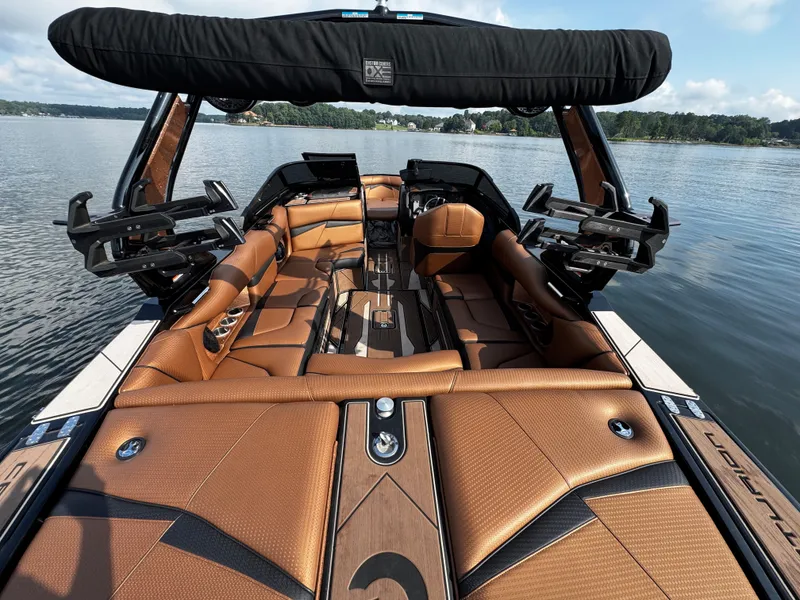 Slide: The Image of 2022 Centurion Fi23 boat interior with luxurious brown seating on a calm lake. - 17