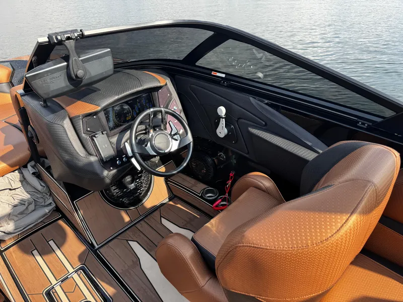Slide: The Image of 2022 Centurion Fi23 boat interior with brown seats and modern dashboard on water. - 20