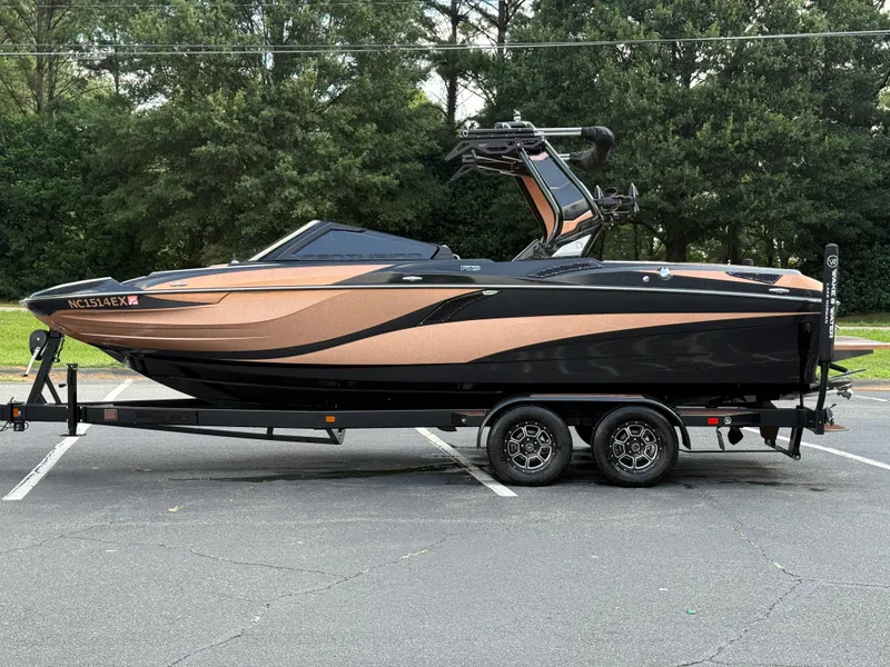 Slide: The Image of 2022 Centurion Fi23 boat on trailer, parked in lot, surrounded by trees. - 3