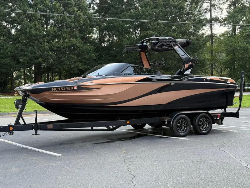 Slide: The Image of 2022 Centurion Fi23 boat on trailer, parked in a lot with trees in the background. - 4