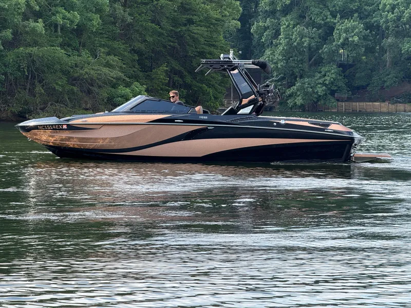 Slide: The Image of 2022 Centurion Fi23 boat cruising on a serene lake with lush green trees. - 6