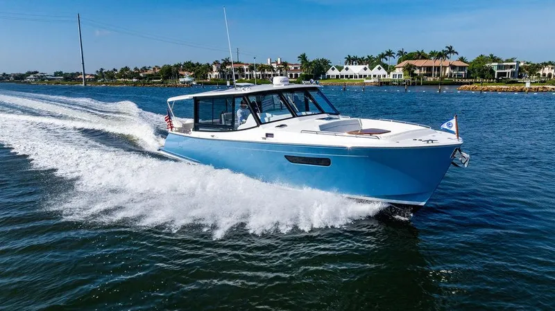 Slide: The Image of 2024 MJM 4 boat cruising on a sunny day near waterfront homes. - 1