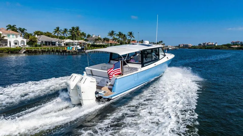 Slide: The Image of 2024 MJM 4 boat cruising on a sunny day, with waterfront homes and palm trees in the background. - 10