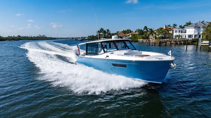 Slide: The Image of 2024 MJM 4 boat cruising on a sunny day, creating a wake in a scenic waterway. - 11