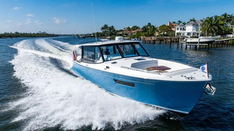 Slide: The Image of 2024 MJM 4 boat cruising on a sunny day near waterfront homes. - 12