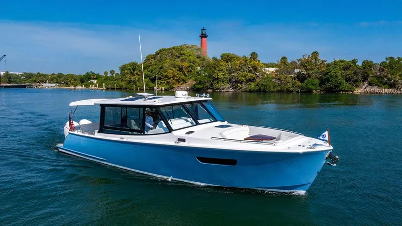 Slide: The Image of 2024 MJM 4 boat cruising on a scenic waterway with a lighthouse in the background. - 21