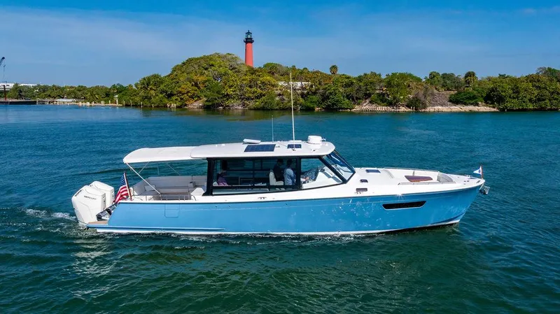 Slide: The Image of 2024 MJM 4 boat cruising on a sunny day near a lighthouse and lush greenery. - 22