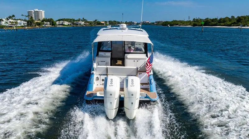 Slide: The Image of 2024 MJM 4 boat cruising on a sunny day, rear view with twin engines. - 4