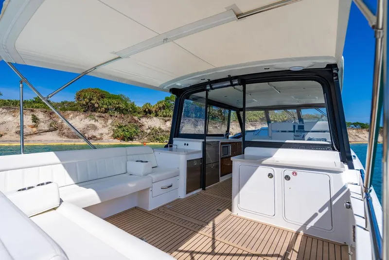 Slide: The Image of 2024 MJM 4 yacht interior with white seating, wooden flooring, and coastal view. - 45