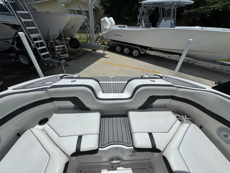 Slide: The Image of 2015 Yamaha Boats AR240 HO interior with seating and deck, parked near other boats. - 33