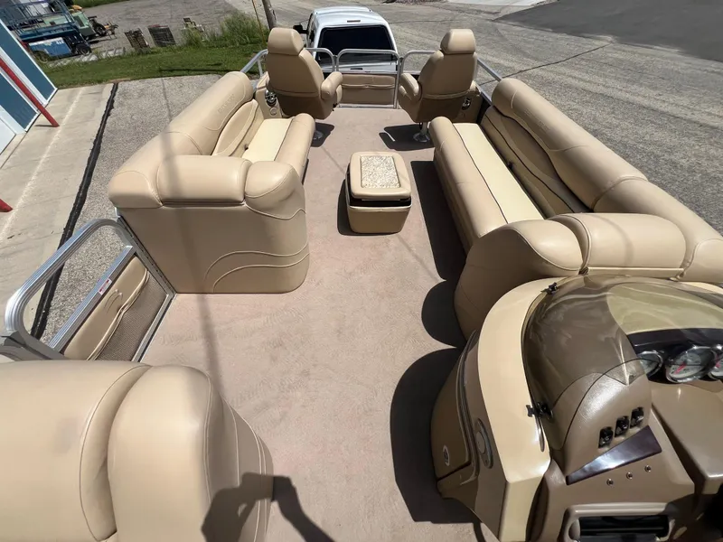 Slide: The Image of 2008 Bennington R25 pontoon boat with beige seating and helm, parked on pavement. - 35