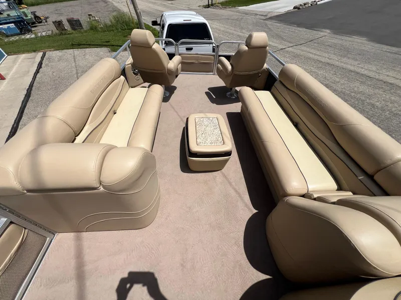 Slide: The Image of 2008 Bennington R25 pontoon boat with beige seating and central table, parked on pavement. - 36