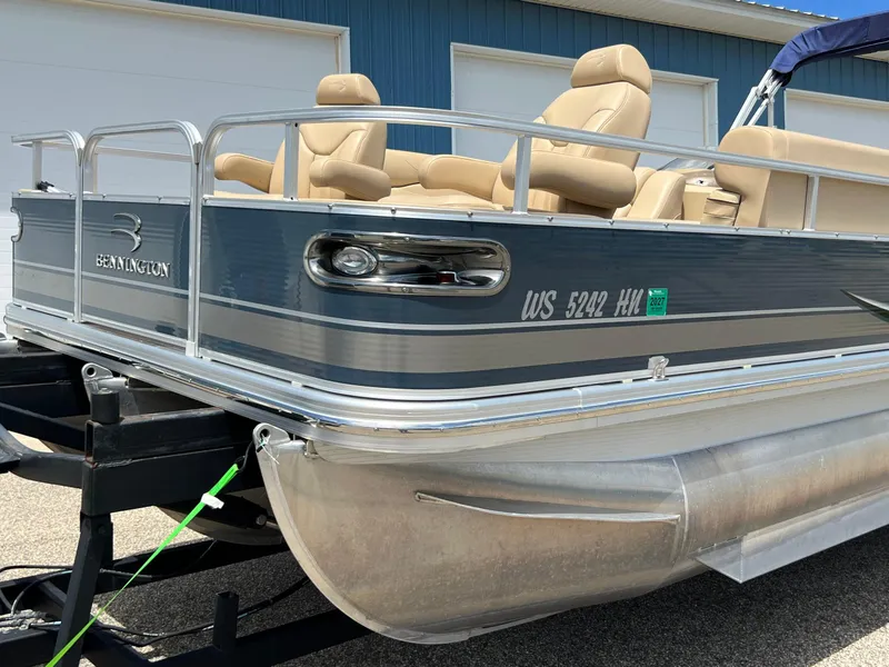 Slide: The Image of 2008 Bennington R25 pontoon boat on trailer, blue exterior, beige seats, parked near blue building. - 38