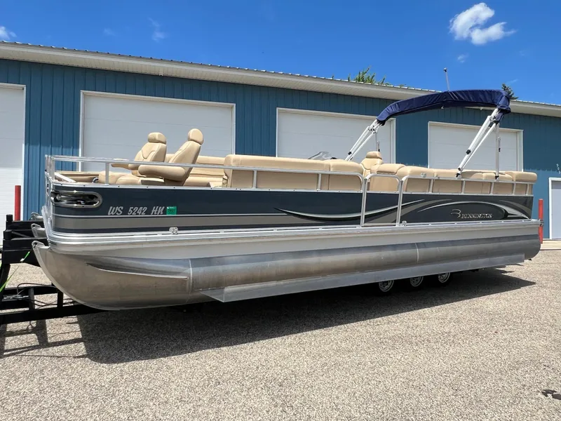 Slide: The Image of 2008 Bennington R25 pontoon boat with beige seating, parked outdoors under a clear blue sky. - 39