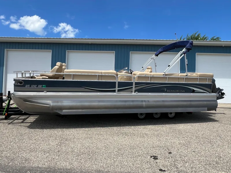 Slide: The Image of 2008 Bennington R25 pontoon boat parked outside a blue building under a clear sky. - 40