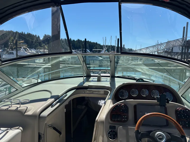 Slide: The Image of 2006 Sea Ray 300 Sundancer cockpit view at marina, clear skies, and scenic background. - 10